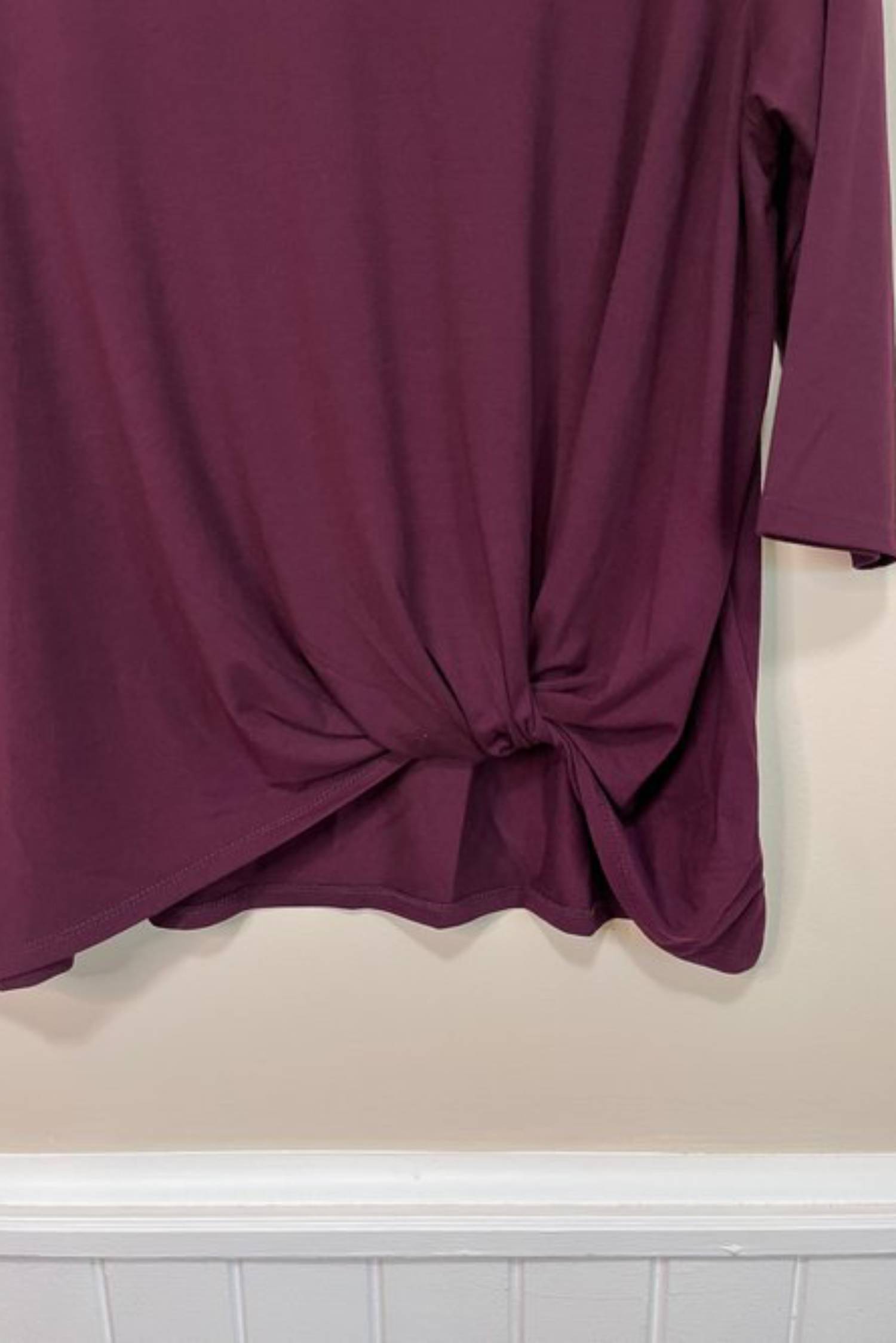 Front hem twist detail of the Tangente Reese Top in Merlot