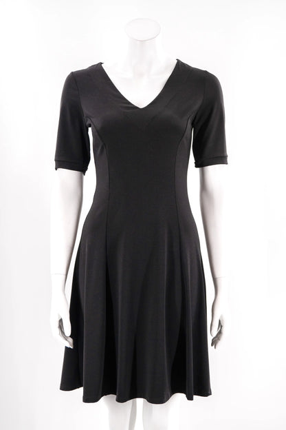 The FW Classic Dress by Karkass in Black, with short sleeves, a v-neck, and fit and flare shape that falls to the knee, is shown on a mannequin against a white background