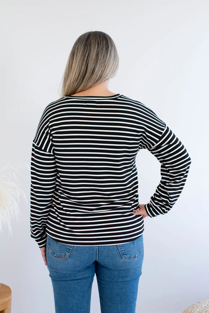 Back view of a woman wearing the Munro Bamboo Crewneck sweater by Ang Hill in black and white stripes. She is wearing it with jeans against a white background.