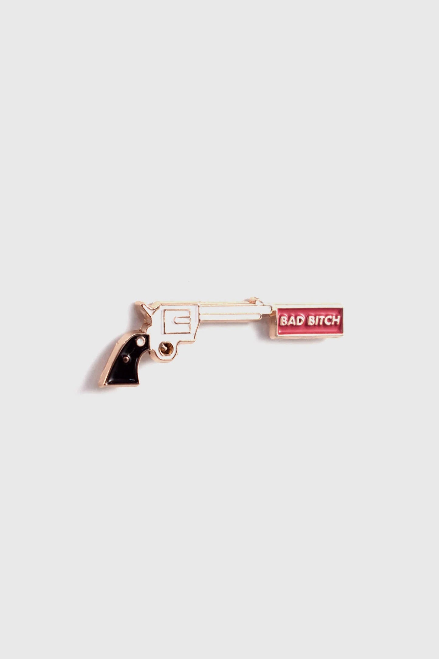 The Bad Bitch Pin by Badaboöm Studio, featuring a gold gun with a red banner that reads "Bad Bitch", is shown against a white background. 