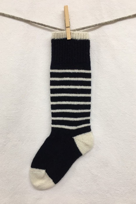 Knitted Socks by Charlevoix Pure Laine in Navy/Grey stripe are shown hanging on a clothesline against a white background