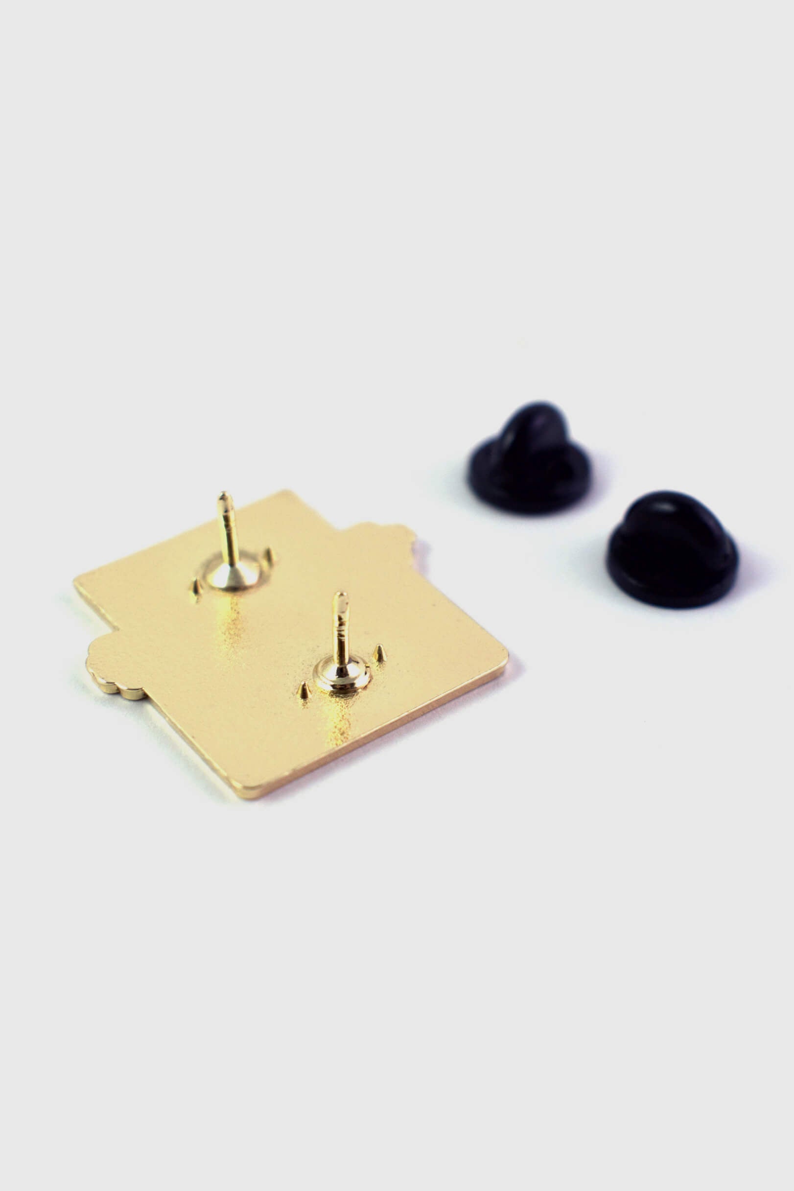 A back view of the Typewriter Pin by Badaboöm Studio, featuring a red typewriter and white paper that reads "Bitch, Please" is shown against a white background. 