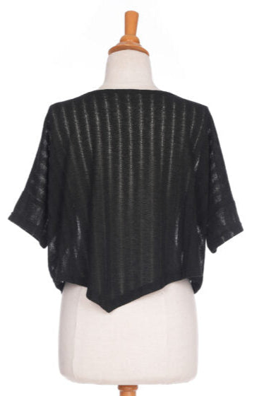 A back view of the Menuet Bolero-Poncho by Rien ne se Perd, a Black woven lightweight poncho, is shown on a mannequin in front of a white background. 