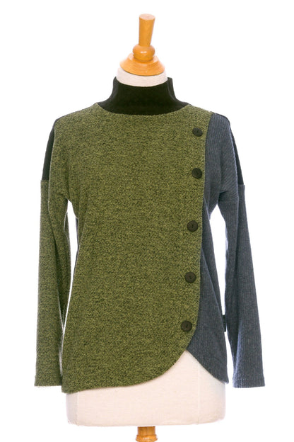 The Chèvrefeuille Sweater by Rien ne se Perd in Sage, a multi-toned piece that's green on the right side, grey on the left, with a black back, is shown on a mannequin in front of a white background.  It has a cross-over front with five black buttons. 