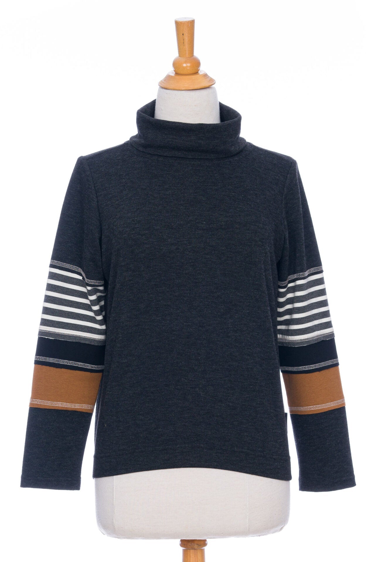 The Chicouté Sweater by Rien ne se Perd in Charcoal/Cognac, with a small turtleneck colour-blocked sleeves, is shown on a mannequin in front of a white background 