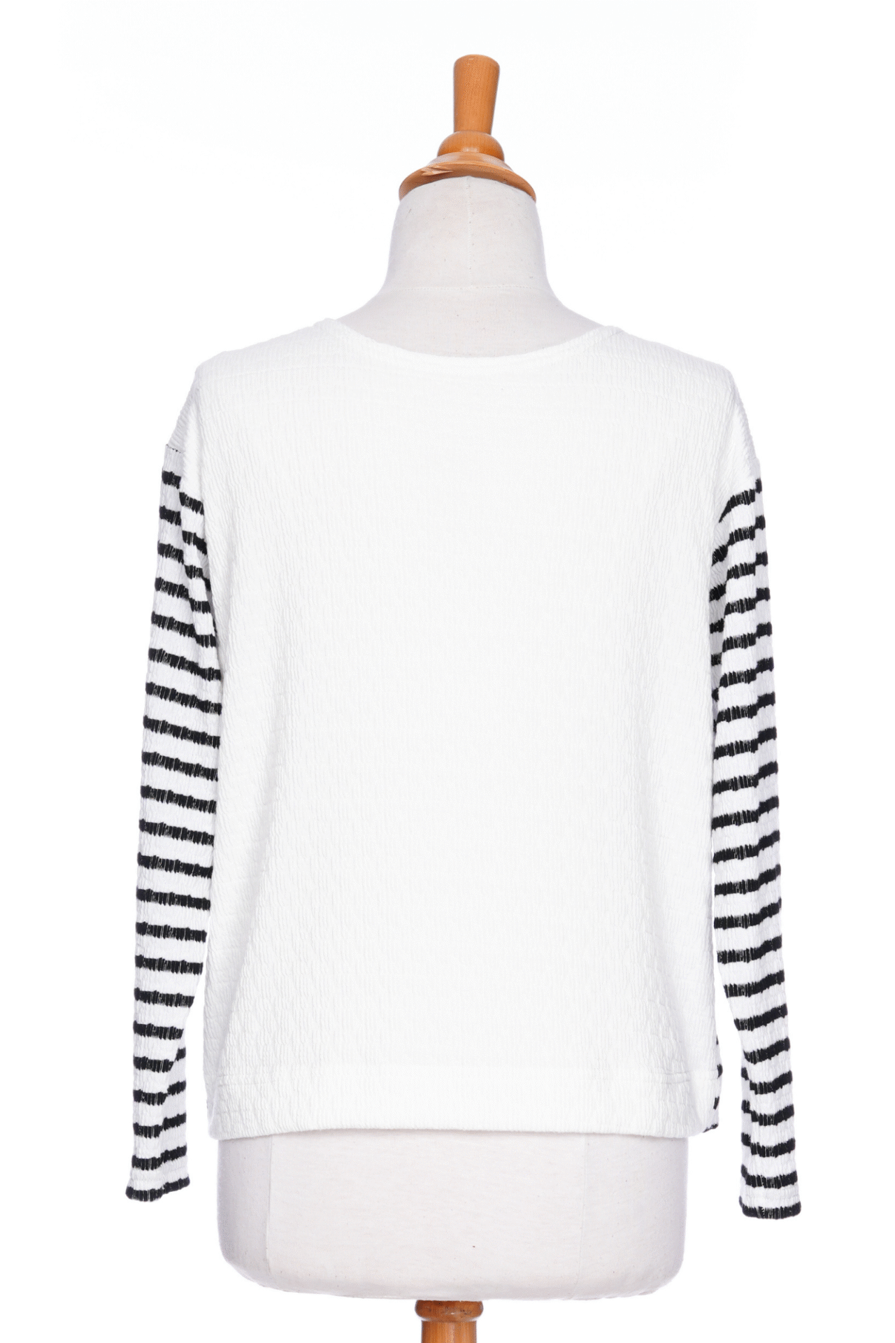 The Collins Reversible Sweater by Rien ne se Perd in Black/White is shown on a mannequin agains ta white background. t's reversible back to front with stripes on side and solid fabric on the other. It has long striped sleeves and a round neck. 