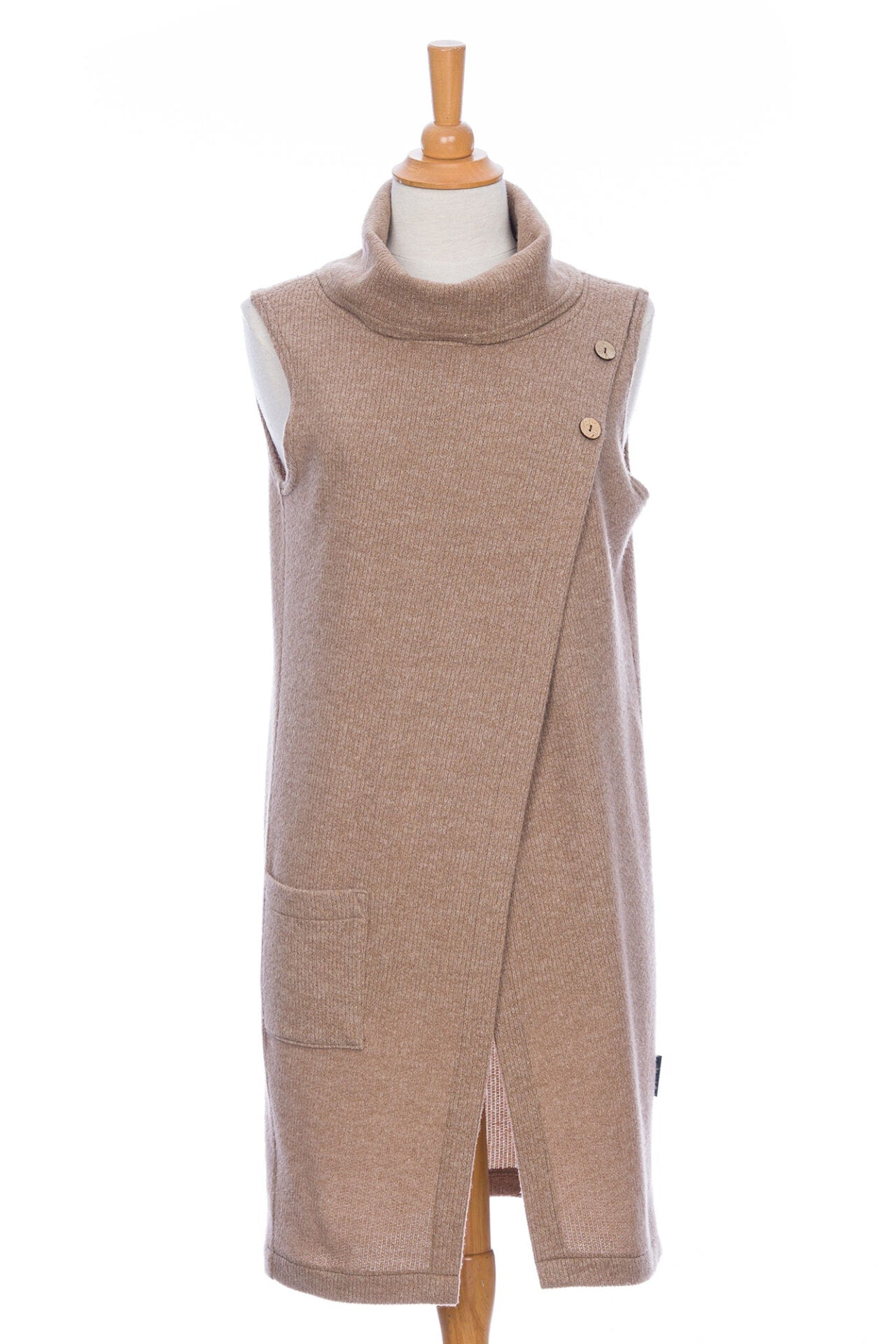 The long Baumier Vest by Rien ne se Perd in Natural, with a cowl neck, overlapping front, buttons and the shoulder and a patch pocket, is shown on a mannequin against a white background. 