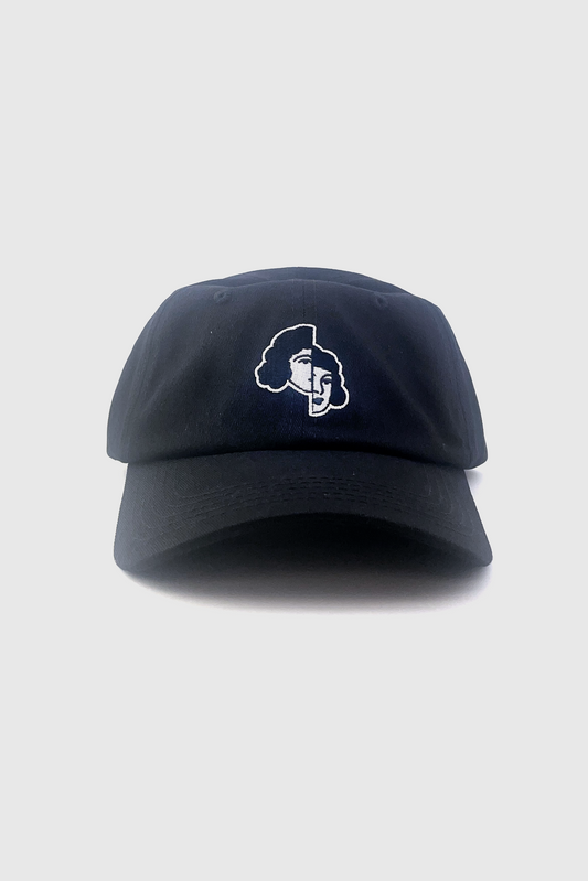 The Split Hat from Badaboöm Studio, featuring an embroidered split view of a woman's face in white on a black background, is shown against a light grey background. 