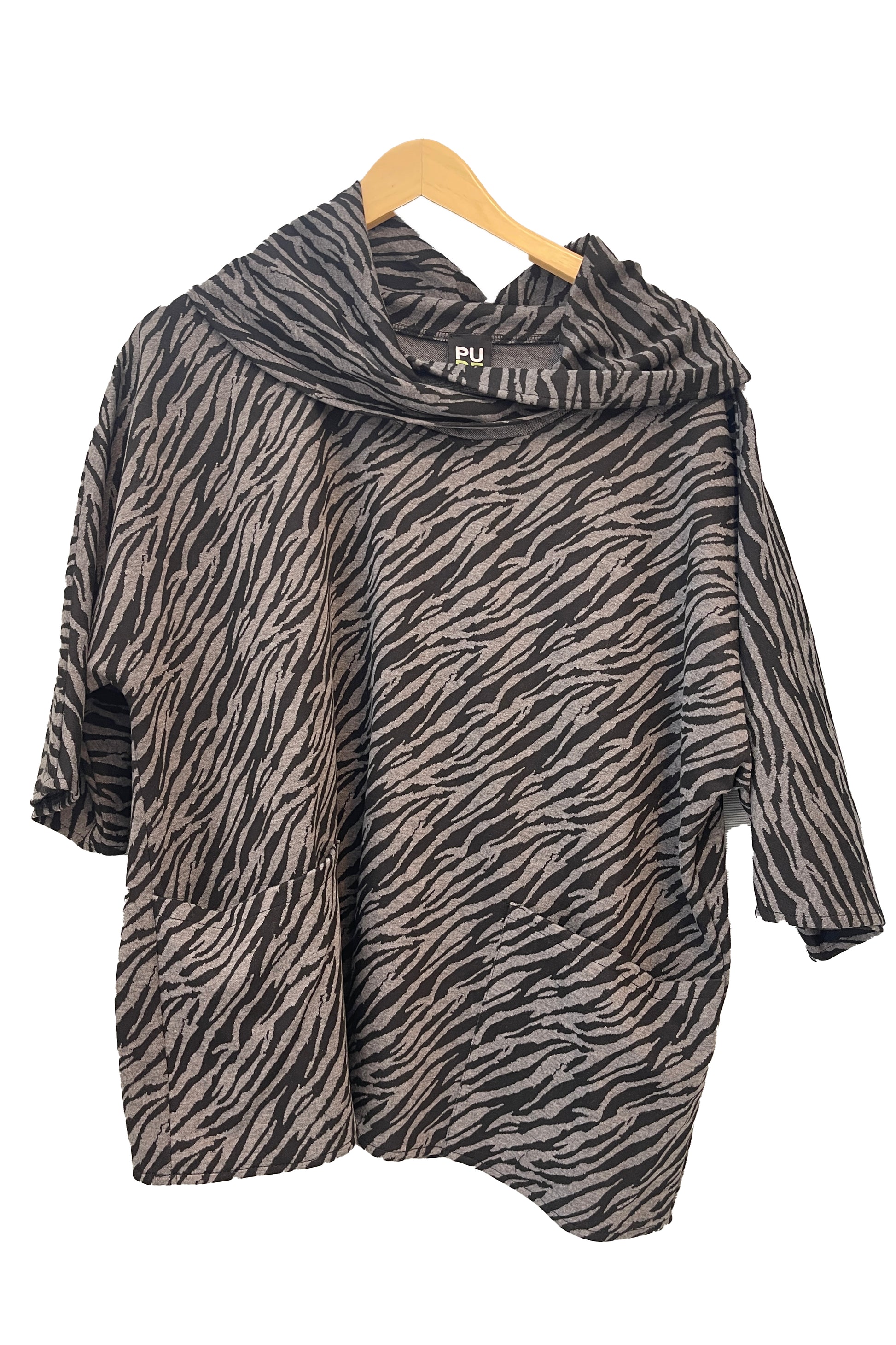 The Francis Tunic by Pure in Black/Charcoal animal print, featuring a turtleneck, 3/4 sleeves and two patch pockets, is shown hanging in front of a white wall. 
