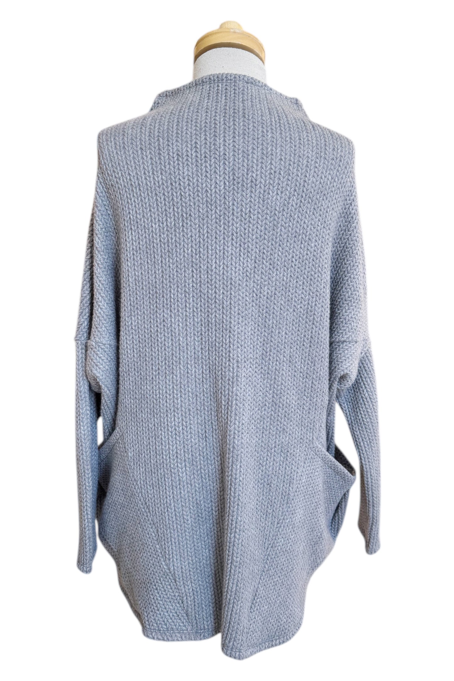 Back view of the Meeso Sweater by MOOVment in Grey, a One Size oversized knit sweater with a wide mock turtleneck, long dropped sleeves and large side pockets, is shown on a mannequin in front of white background. 