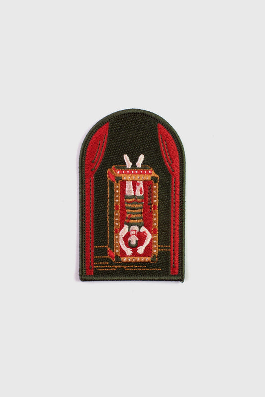 An embroidered arched patch from Badaboöm Studio showing Houdini upside down in a water tank. 
