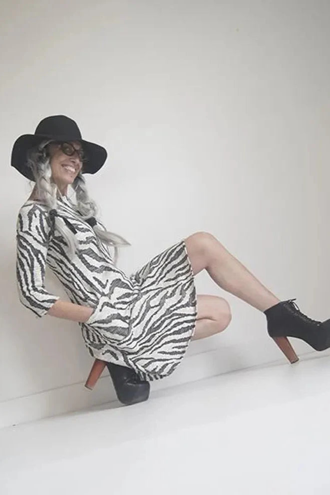 A woman wearing the Casual Dress by SI Design in Ivory/Black, with a round neck, 3/4 sleeves, a loose fitting A-line shape, and a knee length, posing in front of a w white background 