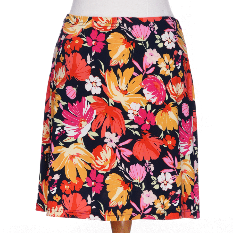 A back view of the Cocktail Skort by Rien ne se Perd in Red/Orange floral print, an elastic waist miniskirt with built-in matching bike shorts, is shown on a mannequin against a white background.