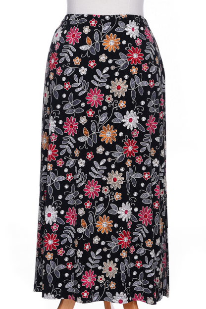 The Fiesta 7/8 Skirt by Rien ne se Perd in Colourful Daisies, a slightly A-line skirt with an elastic waist and side slits, is shown on a mannequin against a white background 