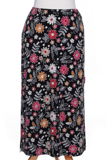 A back view of the Fiesta 7/8 Skirt by Rien ne se Perd in Colourful Daisies, a slightly A-line skirt with an elastic waist and side slits, is shown on a mannequin against a white background 