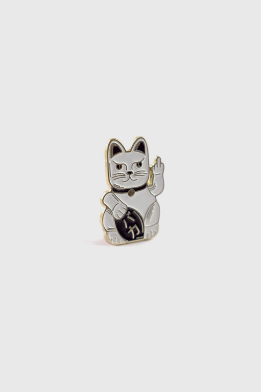 The Lucky Cat Pin from Badaboöm Studio, a small enamel pin shaped like a fortune cat whose giving the finger, is shown against a white background. 