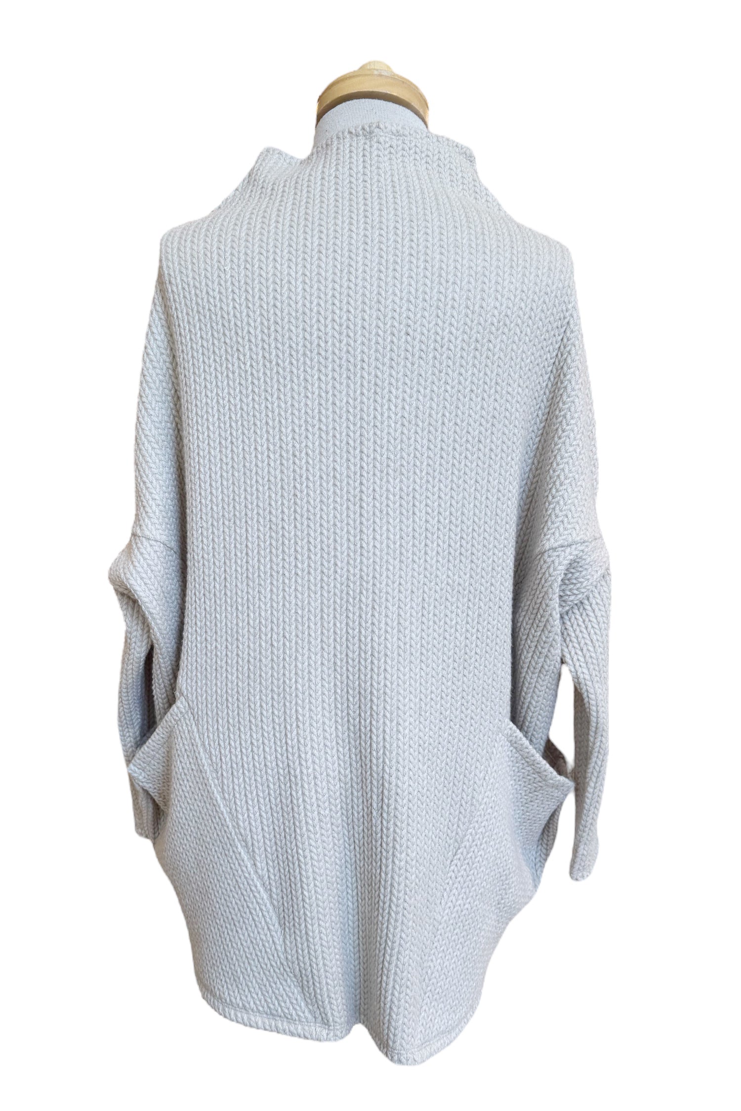 Back view of the Meeso Sweater by MOOVment in Lilac, a One Size oversized knit sweater with a wide mock turtleneck, long dropped sleeves and large side pockets, is shown on a mannequin in front of white background. 