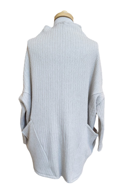 Back view of the Meeso Sweater by MOOVment in Lilac, a One Size oversized knit sweater with a wide mock turtleneck, long dropped sleeves and large side pockets, is shown on a mannequin in front of white background. 