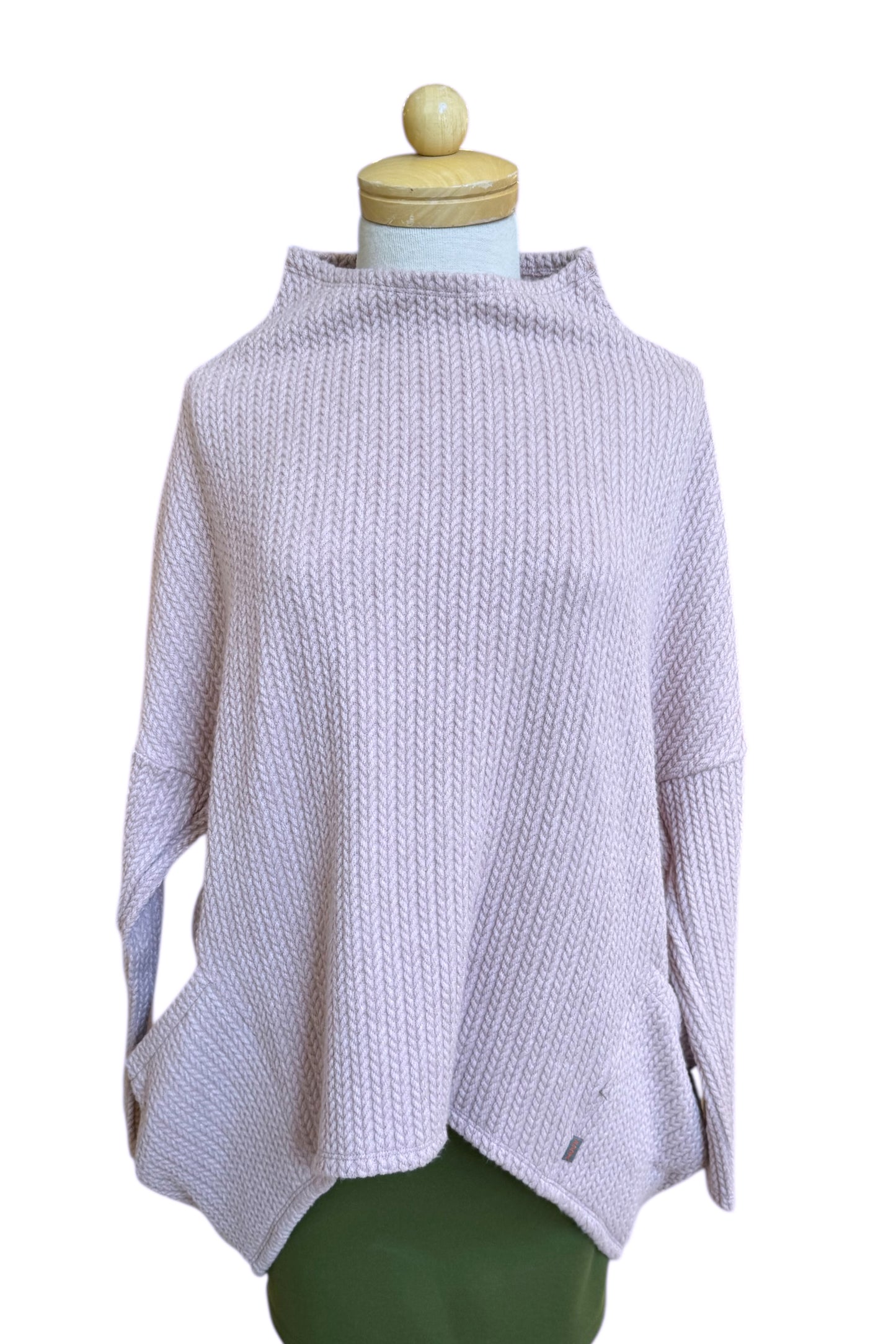 The Meeso Sweater by MOOVment in Rose, a One Size oversized knit sweater with a wide mock turtleneck, long dropped sleeves and large side pockets, is shown on a mannequin in front of white background. 
