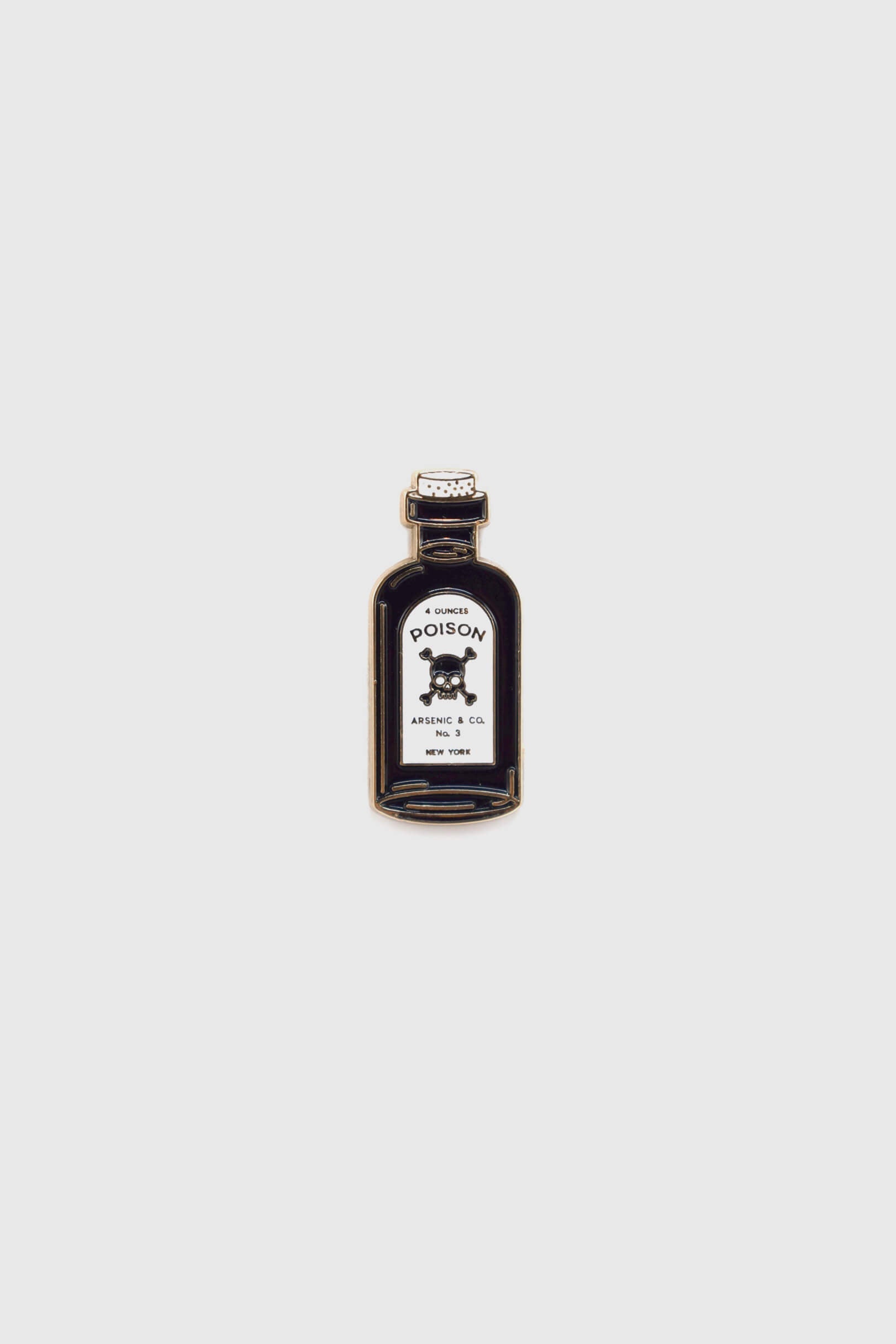 The Poison Pin by Badaboöm Studio, featuring a tiny bottle of poison, is shown against a white background. 