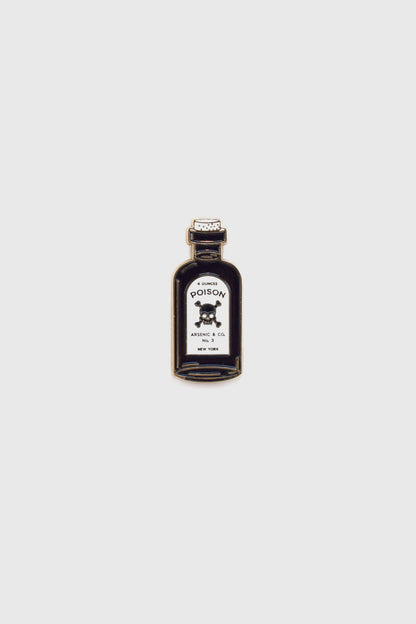 The Poison Pin by Badaboöm Studio, featuring a tiny bottle of poison, is shown against a white background. 