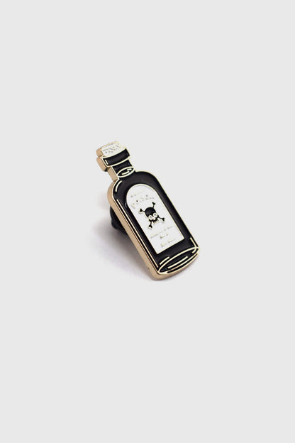 The Poison Pin by Badaboöm Studio, featuring a tiny bottle of poison, is shown against a white background. 