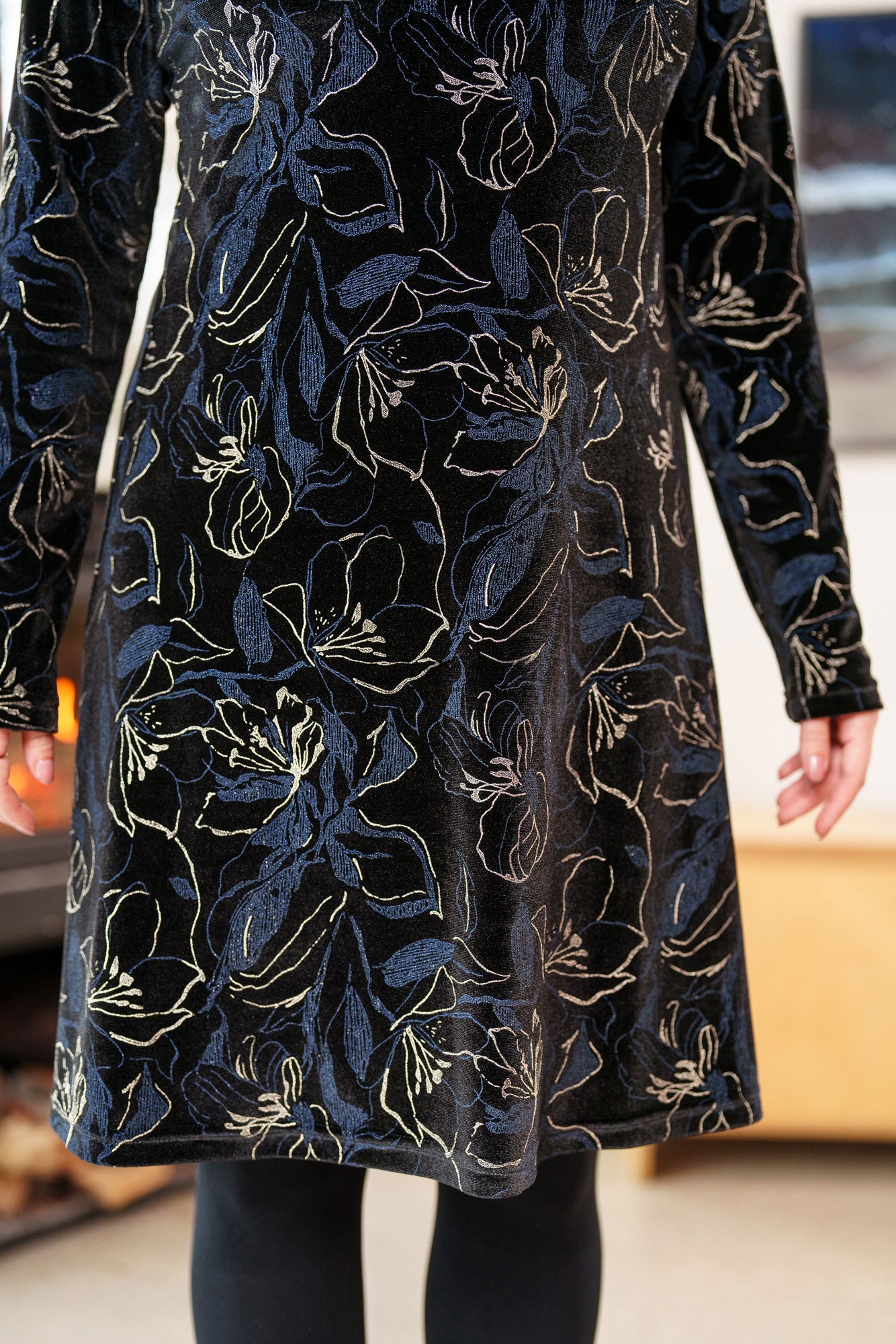 Close up detail of a woman wearing the Larix Dress by Rien ne se Perd in Black/Navy/Gold, a velvet dress with a floral pattern, a round neck, an a knee-length A-line shape.