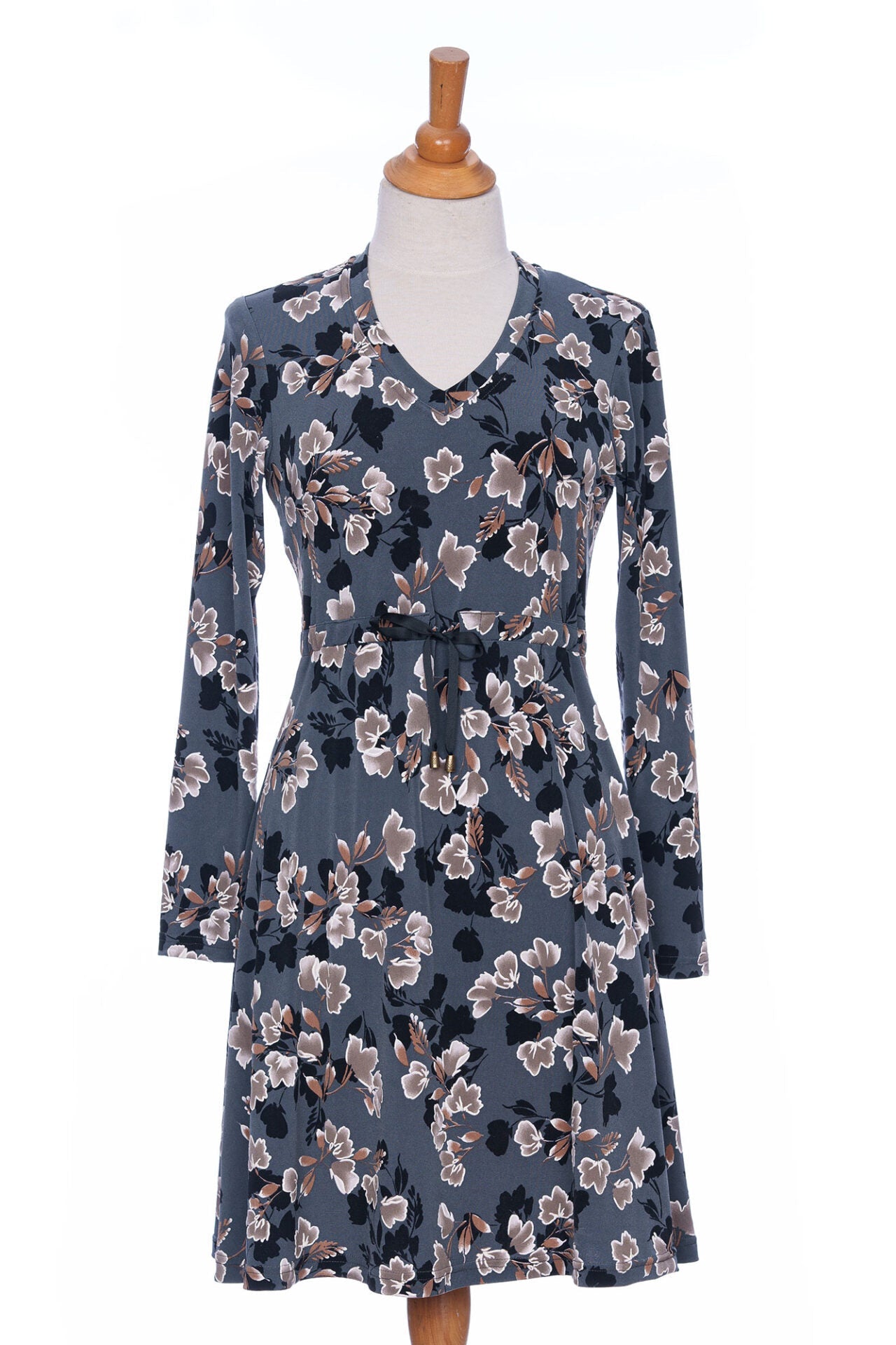 The Mariana Dress by Rien ne se Perd in Blue Floral, featuring a V-neck, an empire waist with a ribbon detail, long sleeves, and a knee-length A-line skirt, is shown on a mannequin in front of a white background. 