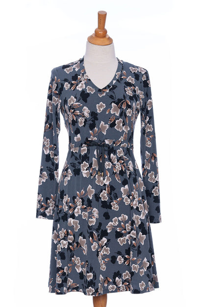 The Mariana Dress by Rien ne se Perd in Blue Floral, featuring a V-neck, an empire waist with a ribbon detail, long sleeves, and a knee-length A-line skirt, is shown on a mannequin in front of a white background. 