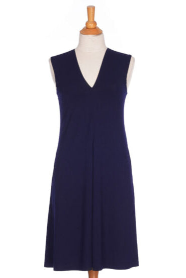 The Samba Dress by Rien ne se Perd in Navy, a sleeveless short dress with a V-neck, centre pleat, and side pockets, is shown on mannequin in front of a white background. 