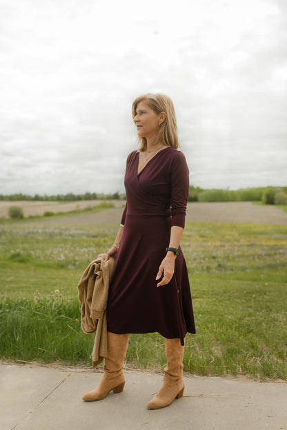 A woman wearing the St-Laurent Dress by Rien ne se Perd in Porto, a midi-length wrap style dress with a 3/4 sleeves and subtle shoulder pleats. She is standing outdoors.