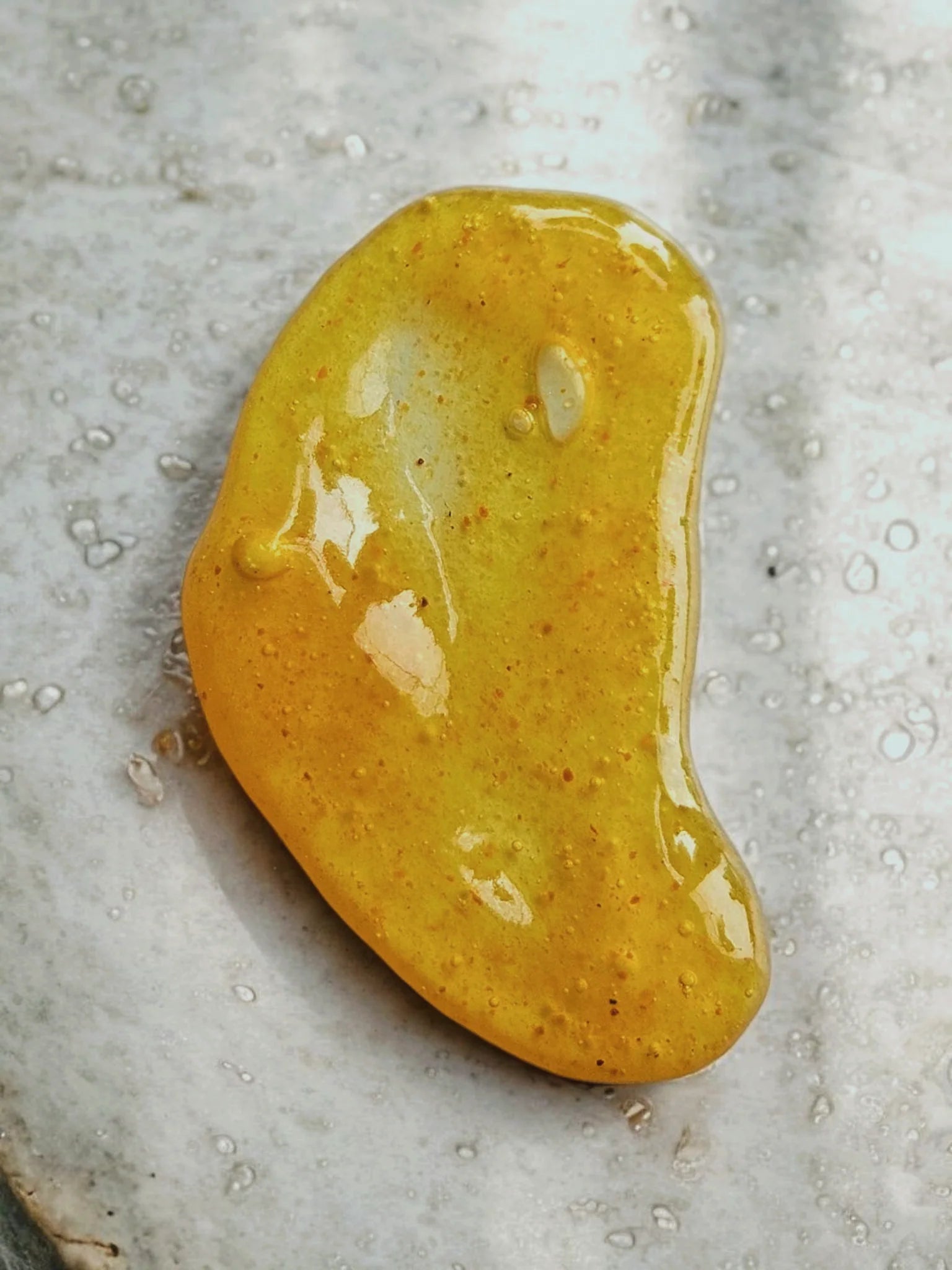 A dollop of Daily Glow face cleaner by Stay Wild Apothecary is shown on a stone surface