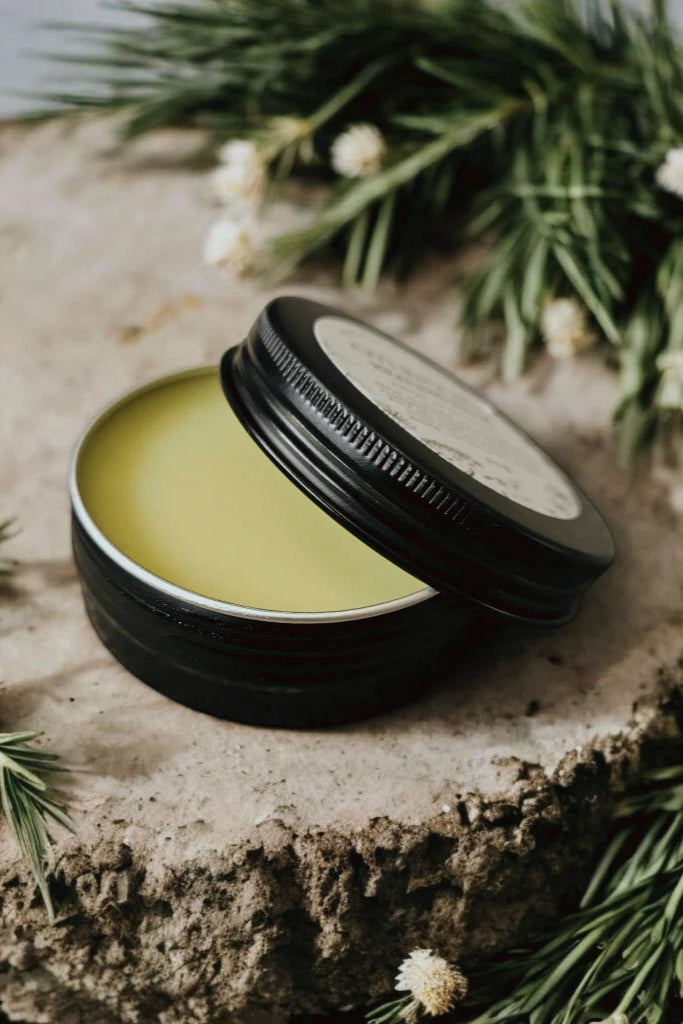 An 'Overnight Healing Balm' container by Stay Wild Apothecary is shown on a wooden surface with natural elements