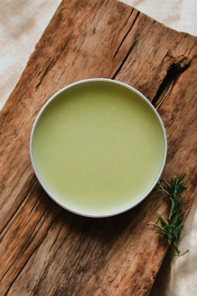 An 'Overnight Healing Balm' container by Stay Wild Apothecary is shown on a wooden surface with natural elements