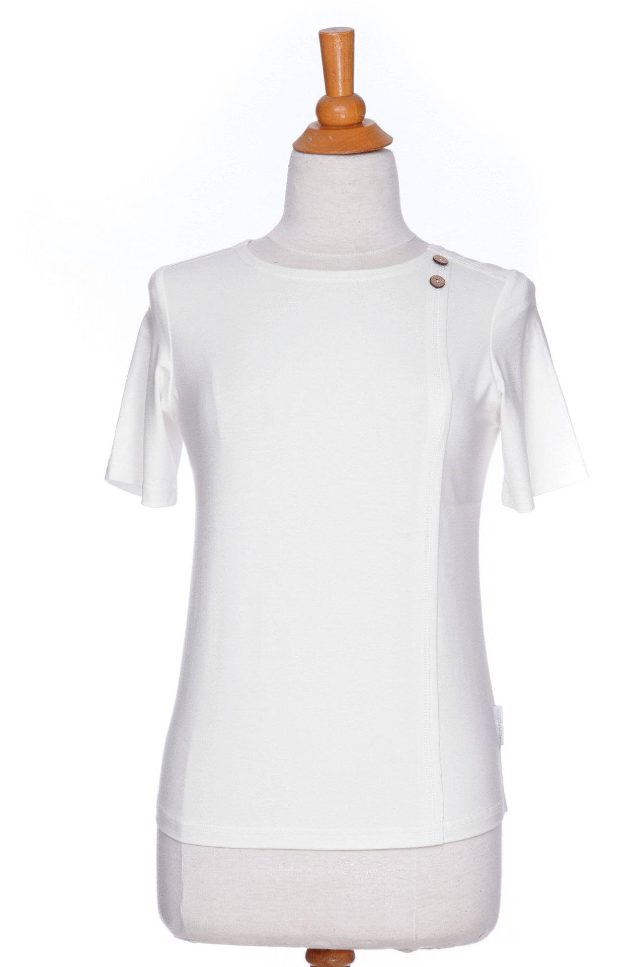 The Mai Tai T-shirt from Rien ne se Perd in Ivory, with coconut buttons at the shoulder, seam accents front and back, and a rounded hi-low hemline, is shown on a mannequin against a white background. 