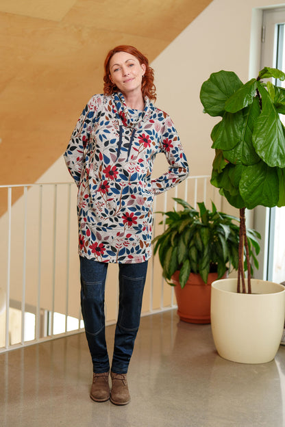 A woman wearing the Cypres Pants by Rien ne se Perd in Blue Denim, stretchy faux denim pants with a pull on waist and tone-on-tone patches on the knees. She is wearing with Genevrier Tunic and standing in front of a railing. 