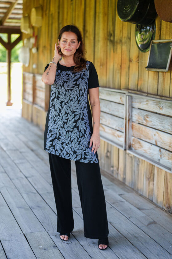 A woman wearing the Rumba Palazzo Pants by Rien ne se Perd in Black, standing outside in front of a wooden background. 