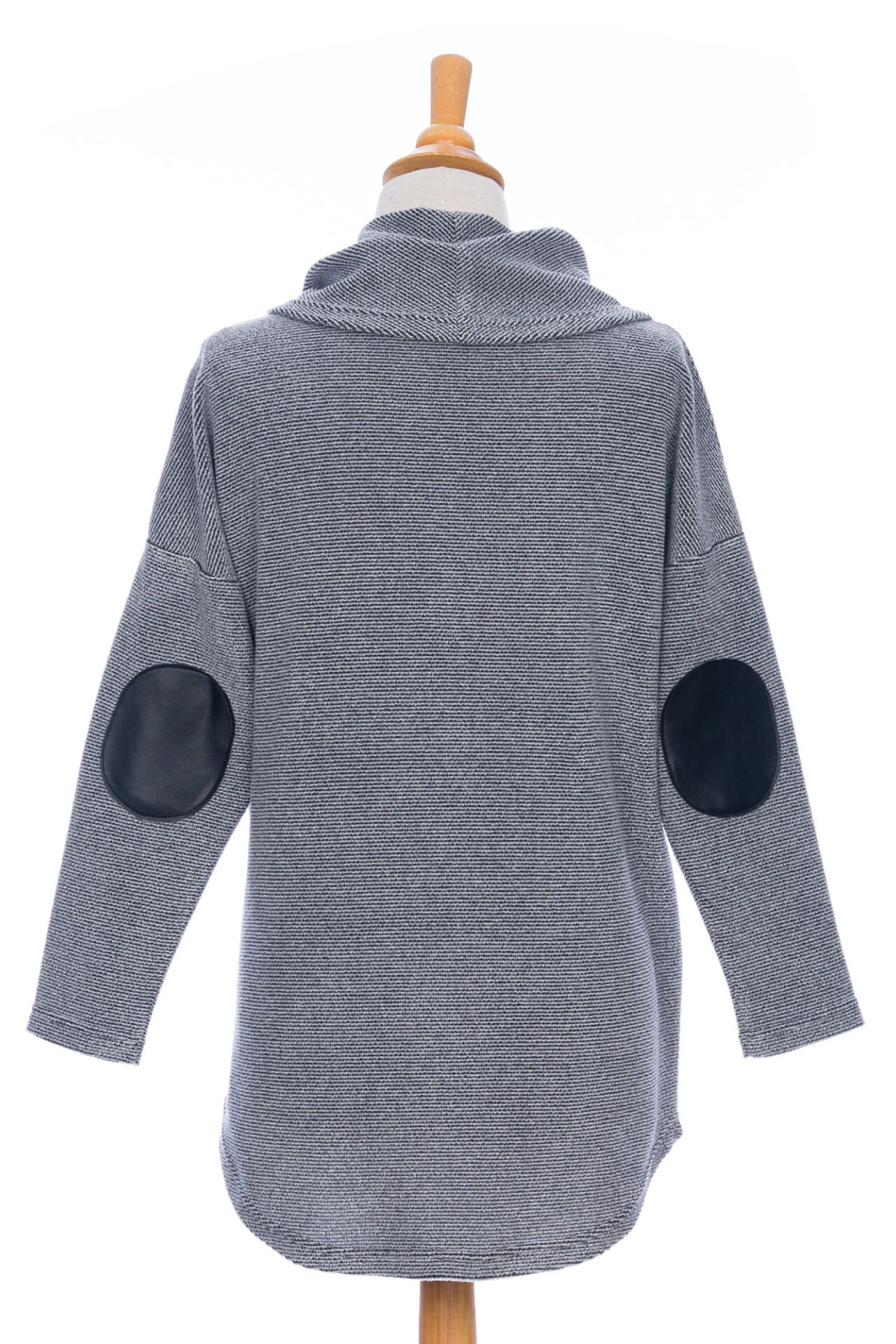 Back view of the Myrique Tunic by Rien ne se Perd in Grey, an oversized chenille tunic with a large cowl neck, rounded hem, faux leather elbow patches, button placket at the left shoulder, and patch pocket on the front, is shown on a mannequin in front of a white background. 