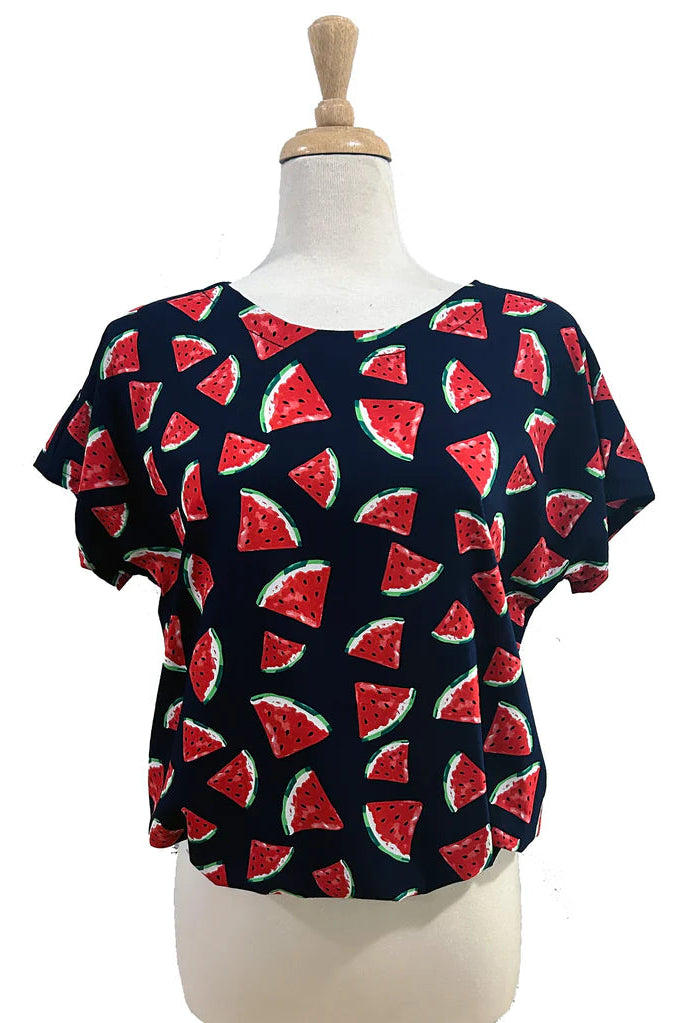 The Macaron Top by Desserts and Skirts in Watermelon, with a round neck, short sleeves, and a loose fit, is shown on a mannequin against a white background. 