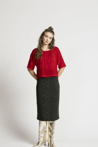 A woman wearing the Wuthering Top by Allison Wonderland in red crushed velvet, with a dark skirt, standing in front of a white background 