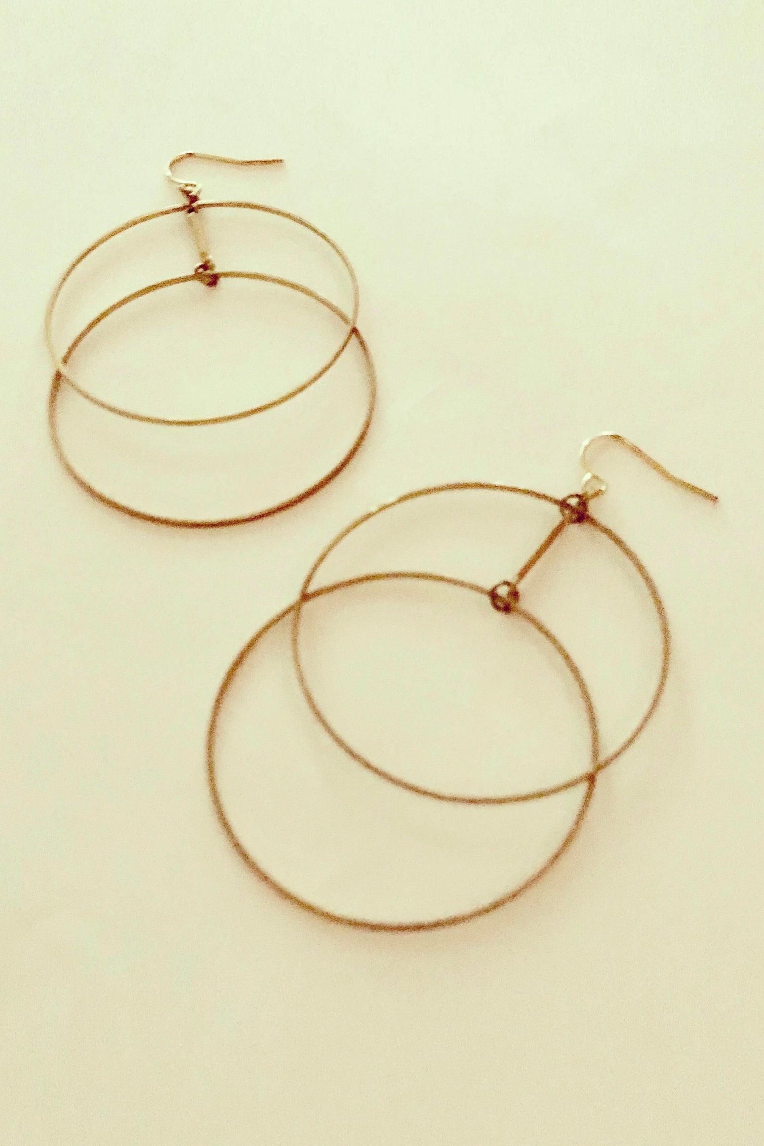 Ruuye earrings by Darlings of Denmark; raw brass; delicate, thin, staggered, double-hoop earrings; flat lay