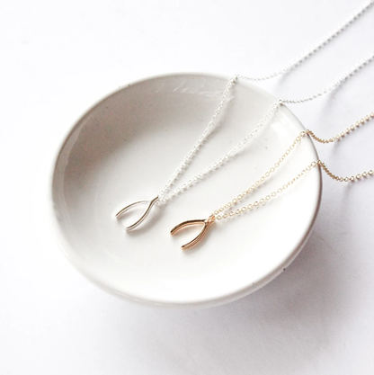 Wishbone necklace by Birch Jewellery; silver and gold plated brass; styled on a white ceramic dish