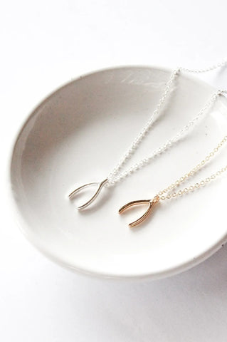 Wishbone necklace by Birch Jewellery; silver and gold plated brass; styled on a white ceramic dish