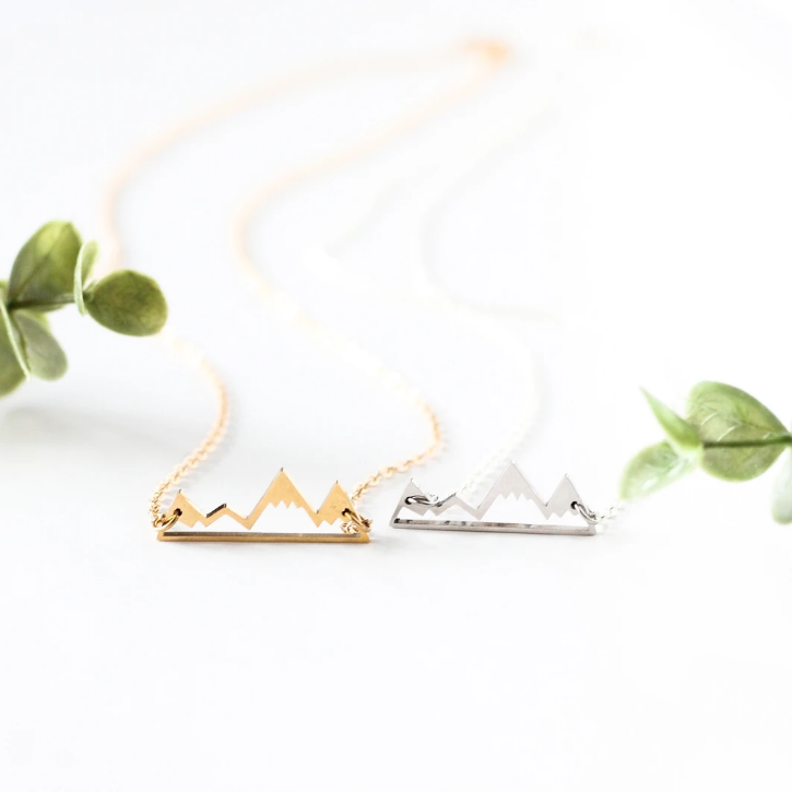 Mountain necklace by Birch Jewellery; silver and gold; flat lay styled with eucalyptus leaves