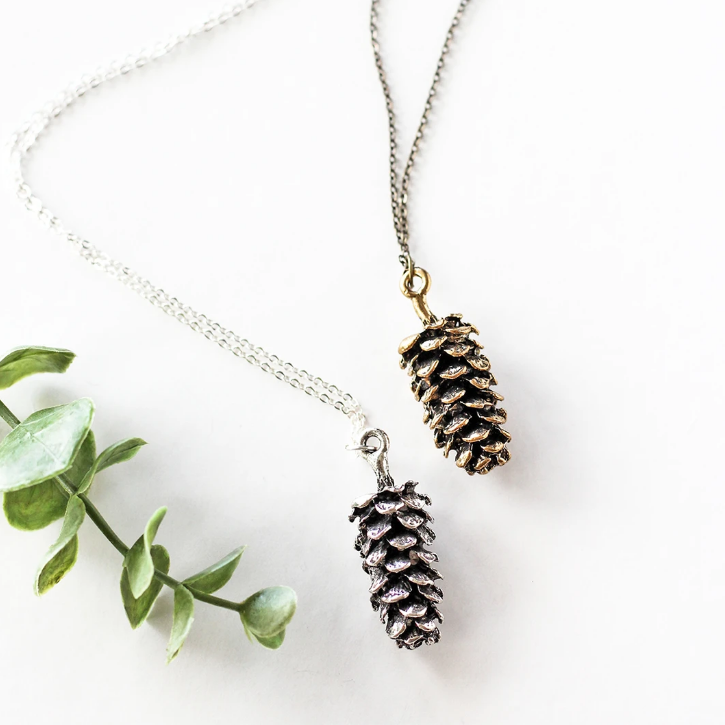 Large pine cone necklace by Birch Jewellery; flat lay; in silver and gold