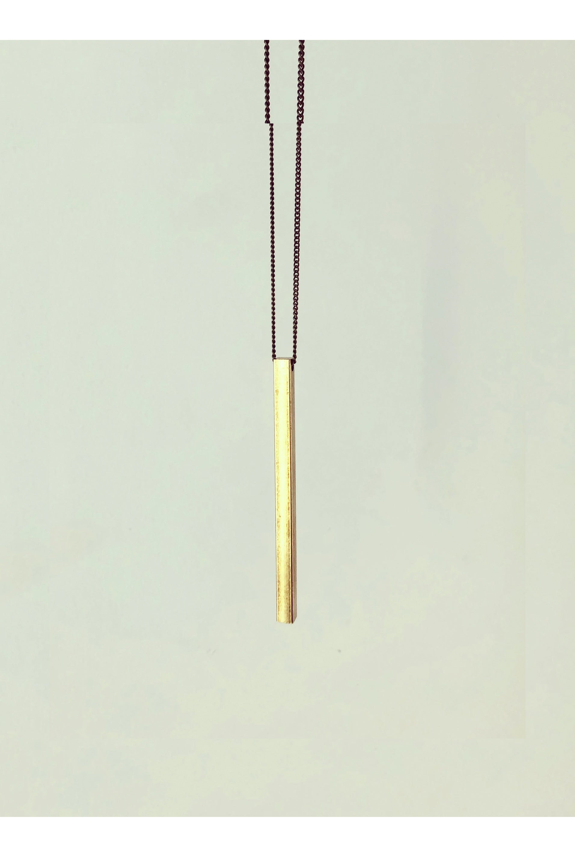 Slik necklace by Darlings of Denmark; raw brass; long solid bar; long chain; close-up shot