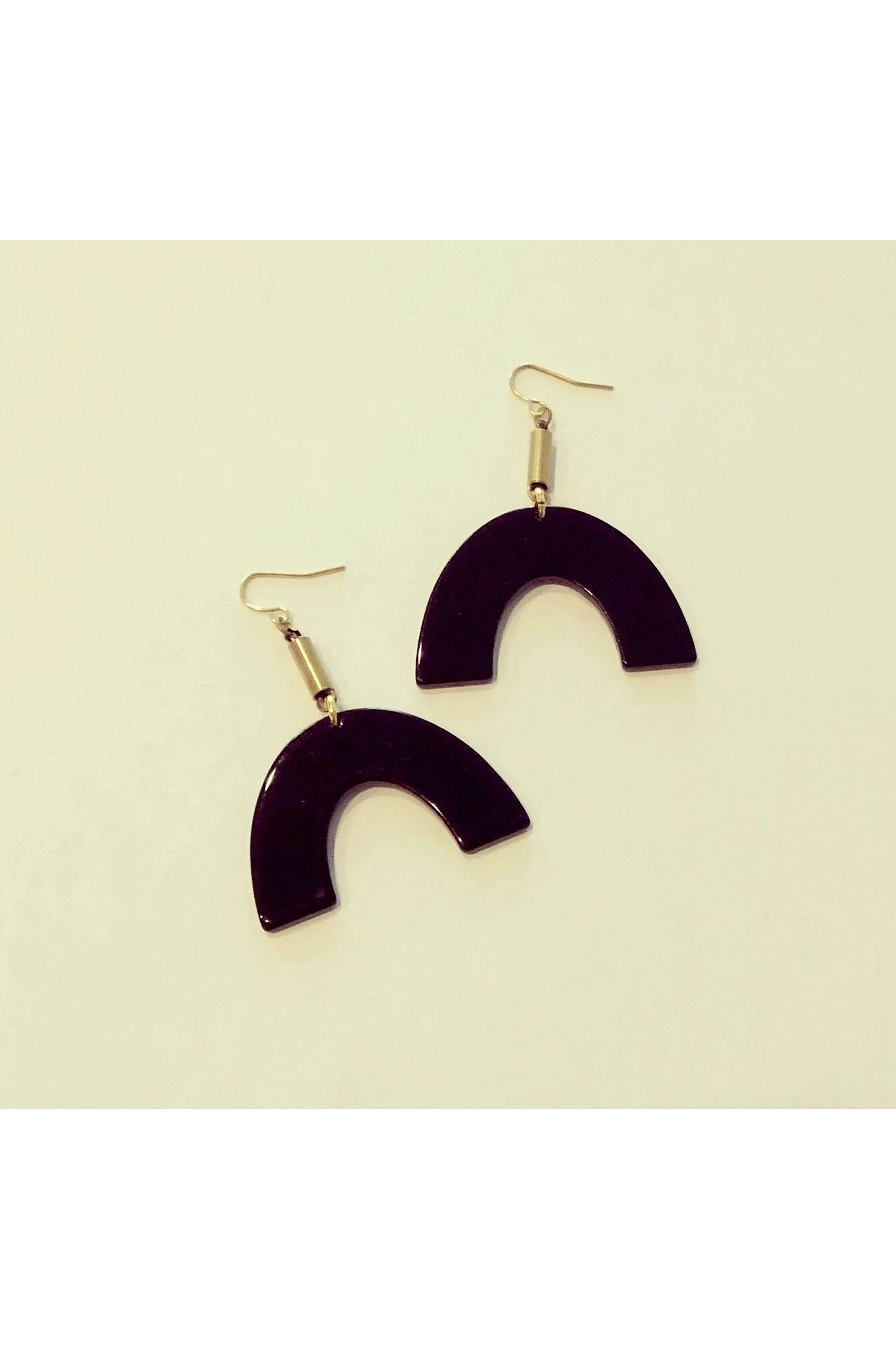 Vuttue dangle earring by Darlings of Denmark; black acrylic arch hanging off raw brass tubes; flat lay